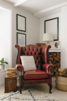 Contemporary open plan living room in a Cornish cottage. Featuring wood burner and red leather wingback armchair.