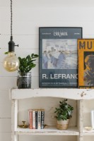 Detail of distressed shelf unit with framed posters and books.