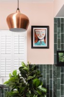 Pendant light and art work in a green tiled bathroom with plantation shutters