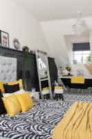 View of monochrome and yellow open plan bedroom with bathtub