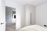 Corner of modern bedroom with built in wardrobe and view through to living room