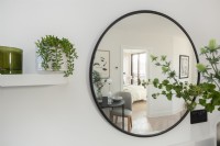 Detail of a round mirror on a wall reflecting the interior of an apartment