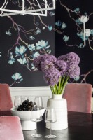 Details of purple flowers and grapes on dining room table and floral wallpaper.