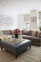 Modern living room with sectional sofa and large leather ottoman as coffee table.