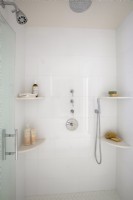 White tiled shower stall with multiple shower heads.