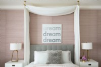 Feminine bedroom in pink and white with a curtained canopy over bed.