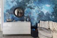 White chest of drawers in front of feature wall with a vinyl world mural.