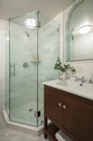 Modern bathroom with glass enclosed shower and white and brown sink unit.