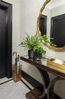 Glass topped console table and gold framed mirror in entrance hall