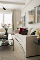 Modern white living room sofa and glass coffee table.