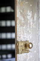 Rustic wooden door with ornate brass door handle in ancient stone cottage