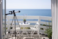Telescope looking out across the sea, white painted balcony.