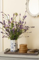 Informal country style vase of flowers on chest of drawers, vintage brush set and small baskets