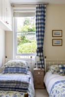 Twin bedroom with pretty farmhouse fabrics in blue and white, brass bed heads