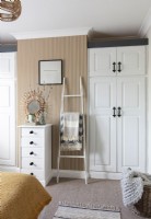 Built-in wardrobes and rustic ladder rail in bedroom