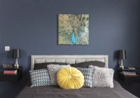 Variety of cushions on bed with a peacock painting on wall above
