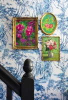 Framed floral paintings on wallpapered wall - hallway detail