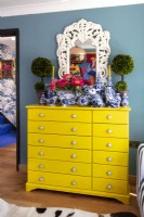 Bright yellow chest of drawers with display of ceramic ornaments