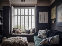 Dark living room with velvet sofa, window seat and plantation shutters