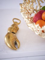 Crab claw bottle opener next to gold fruit bowl