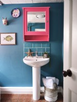 Bathroom sink in blue bathroom with pink mirror
