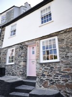 Exterior of the home with pink door and stone walling