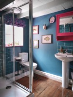 Blue bathroom with artwork and pink mirror