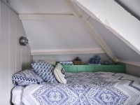 Blue and white bed furnishings in airy loft room 