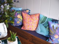 Colourful coastal themed cushions next to white panelled wall