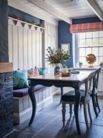 Vintage table, upholstered chairs and a white panelled bench in a coastal themed dining room
