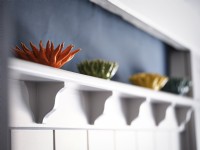 Orange, green and yellow coral carved ornaments on shelf above panelled wall