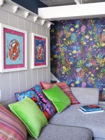 Matching colourful wall artwork and cushions with white panelled walls