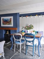 Dining room with coastal inspired colour scheme and a fireplace with marine artwork above