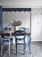 Blue and white upholstered chairs in dining room with white panelling 