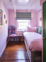 Pink bedroom with vintage upholstered chair and soft furnishings 
