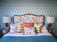 Colourful coastal bedding on upholstered bed next to coral sculptured lamps