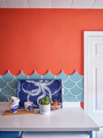 Coastal inspired tray and cups in front of sea blue tiles and a red wall 