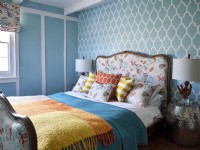 Upholstered bed in front of blue and white patterned wall 