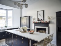 Classic kitchen featuring island unit, bar stools and decorative mantel piece