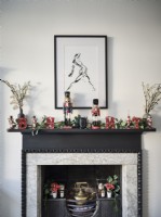 Mantel decorated in ornaments and plants below artwork
