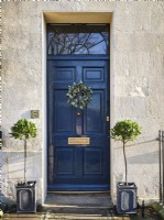 Black door with Christmas wreath and symmetrical plants
