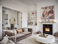 Neutral open living room with fireplace, beige soft furnishings and circular coffee table