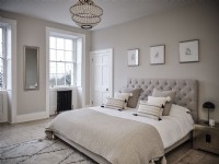 Neutral bedroom featuring a bed, wall art and two windows
