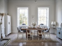 Classic dining table and chairs and two large windows in neutral dining room 