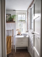White bathroom featuring exposed pipes and brickwork and house plants