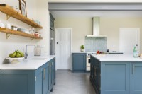 Modern classic kitchen with blue cupboards, island, open shelves, concrete floor tiles and exposed steel beam.