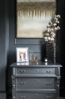 Black painted chest of drawers in black and gold bedroom