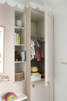 View of clothes in open wardrobe in childrens room