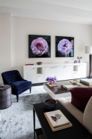 Modern living room with long white credenza decorated with photographs of flowers on wall.