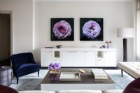 Modern living room with long white credenza decorated with photographs of flowers on wall.